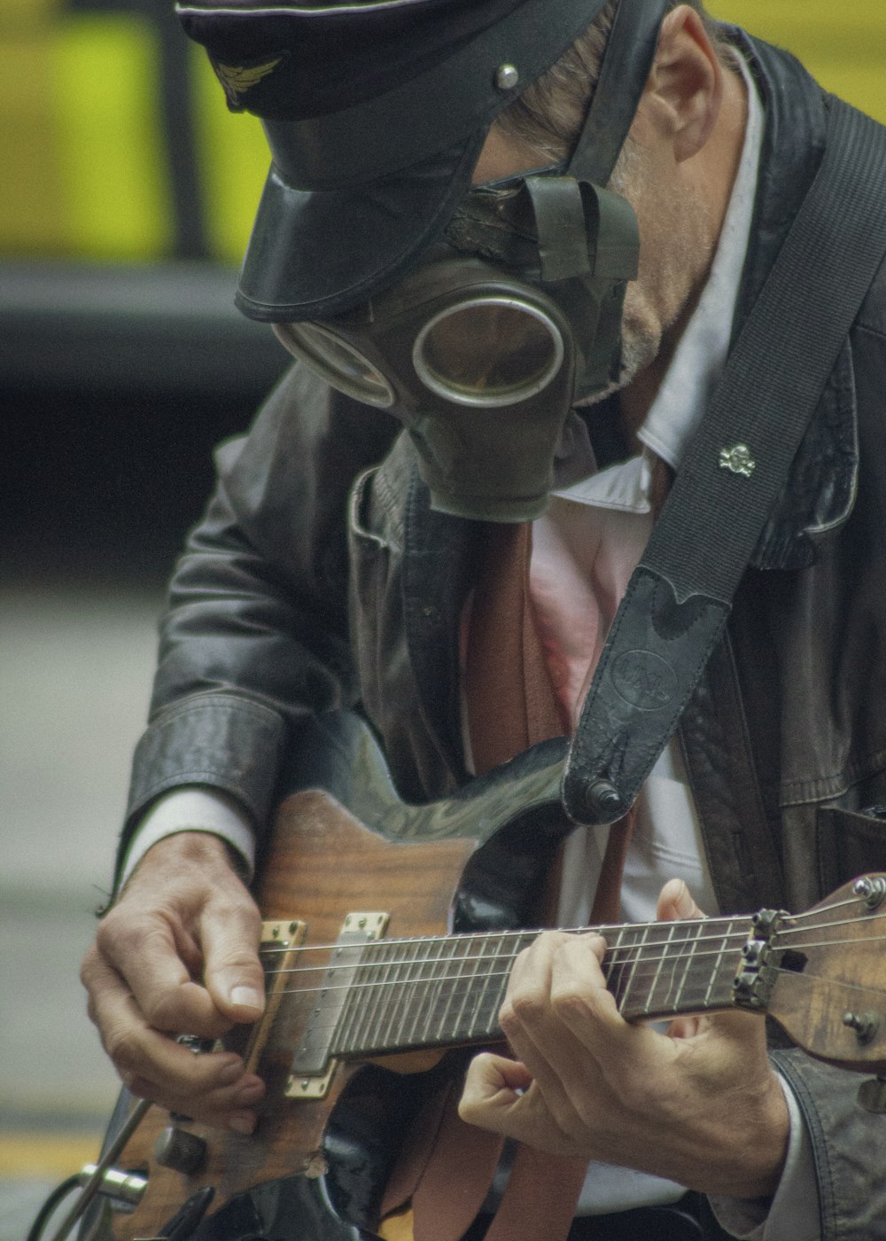 un homme portant un masque à gaz jouant de la guitare