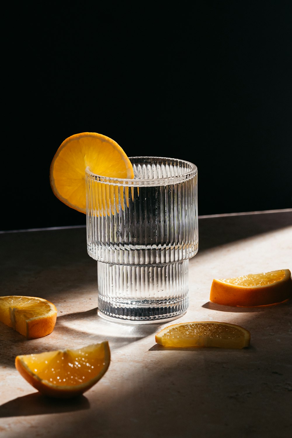 a glass of water with a slice of orange next to it