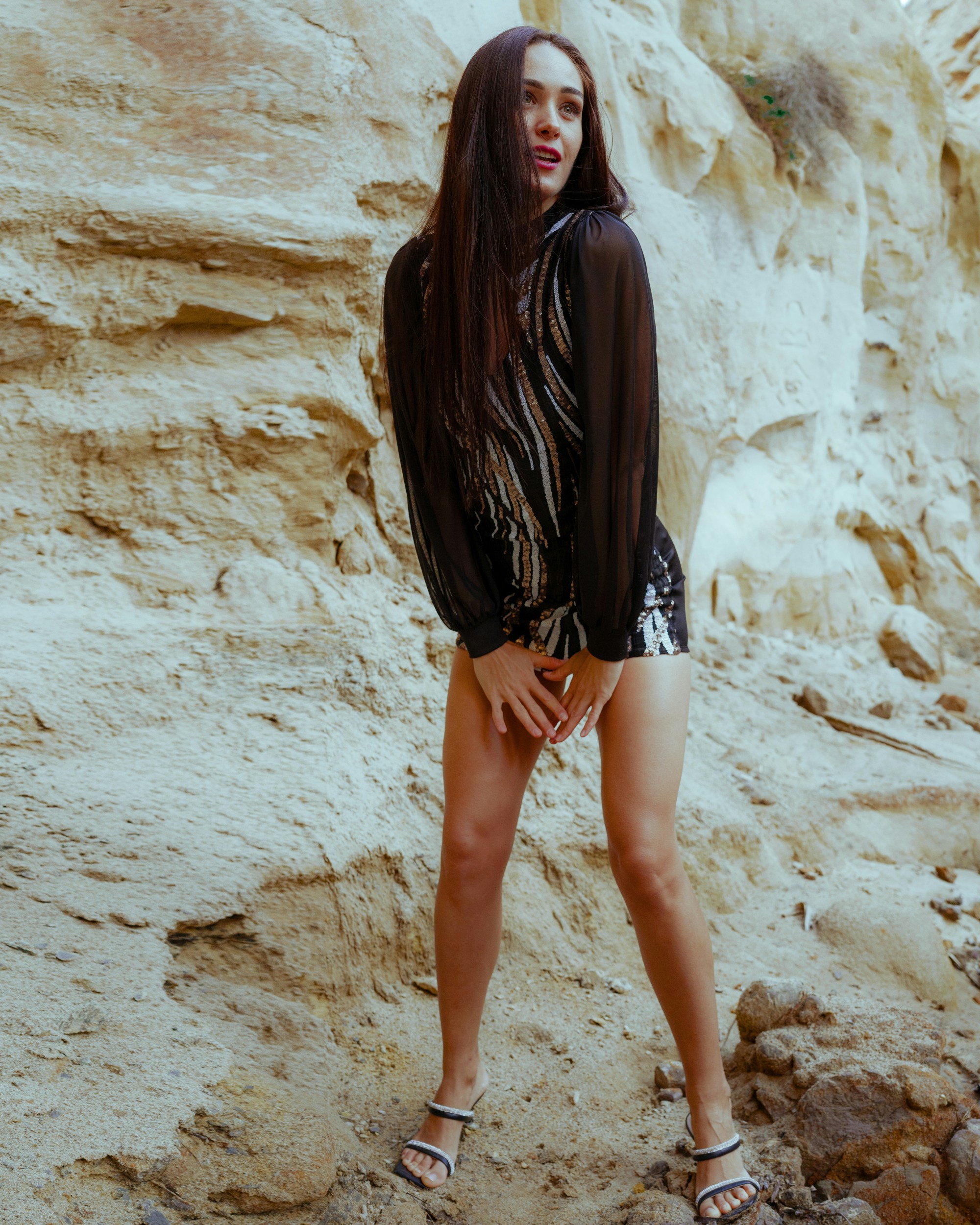 a woman standing in front of a rocky cliff