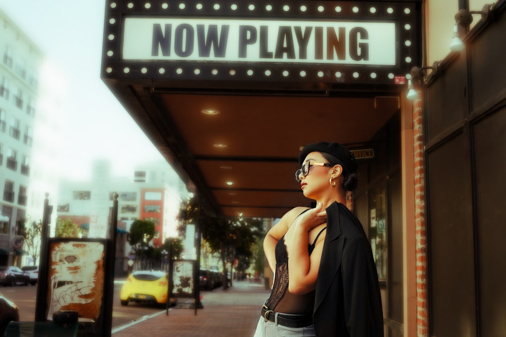 a woman standing in front of a theater sign