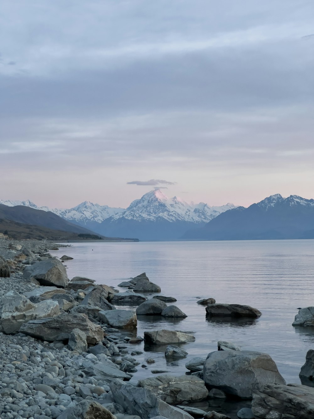 ein felsiger Strand mit einer Bergkette im Hintergrund