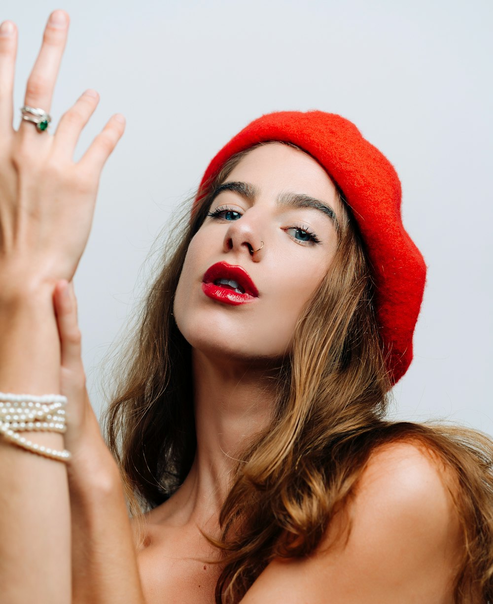 a woman wearing a red hat and holding her hand up