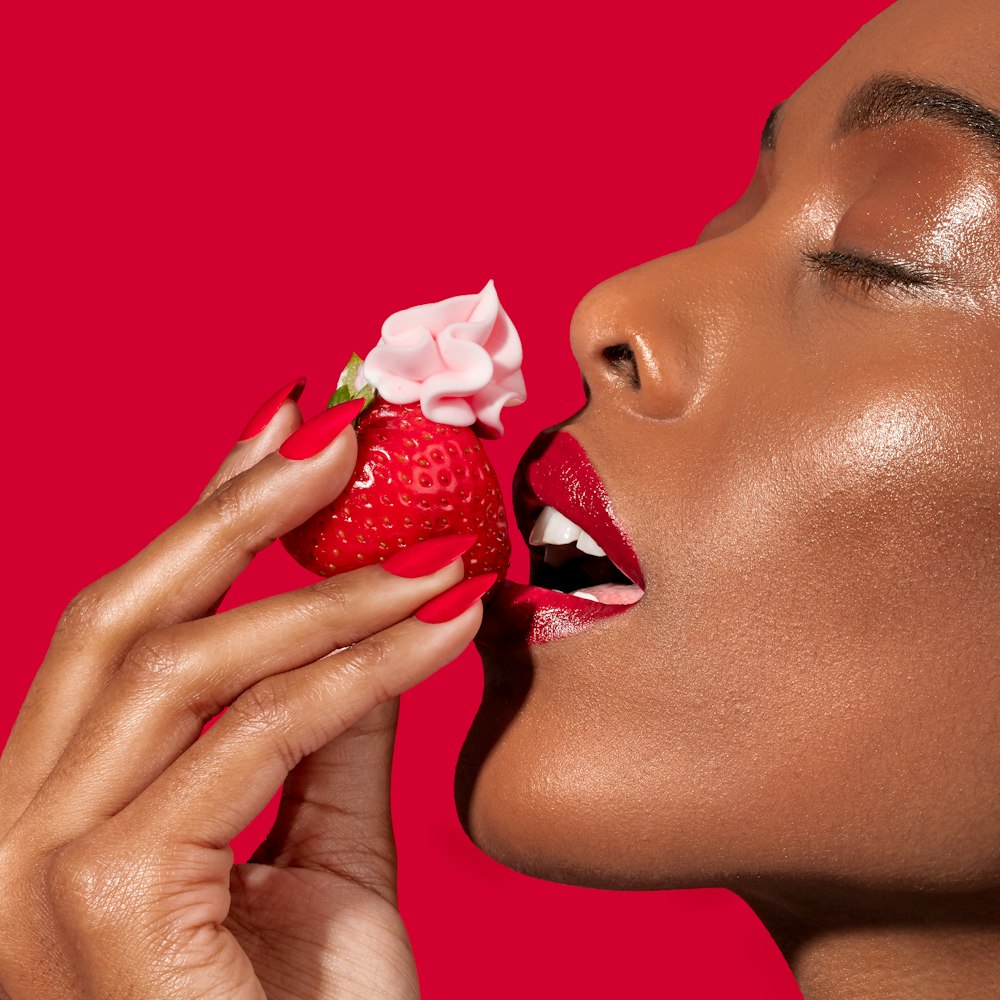 a woman eating a strawberry with a flower on it