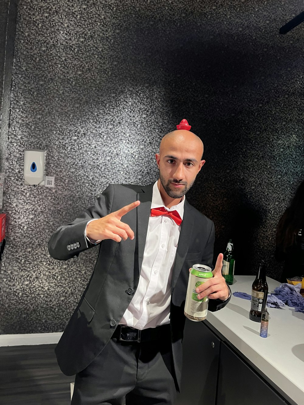 a man in a suit and bow tie holding a drink