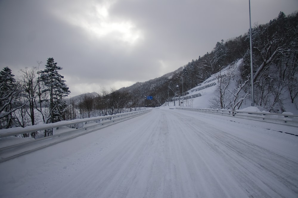 a snow covered road with trees and mountains in the background