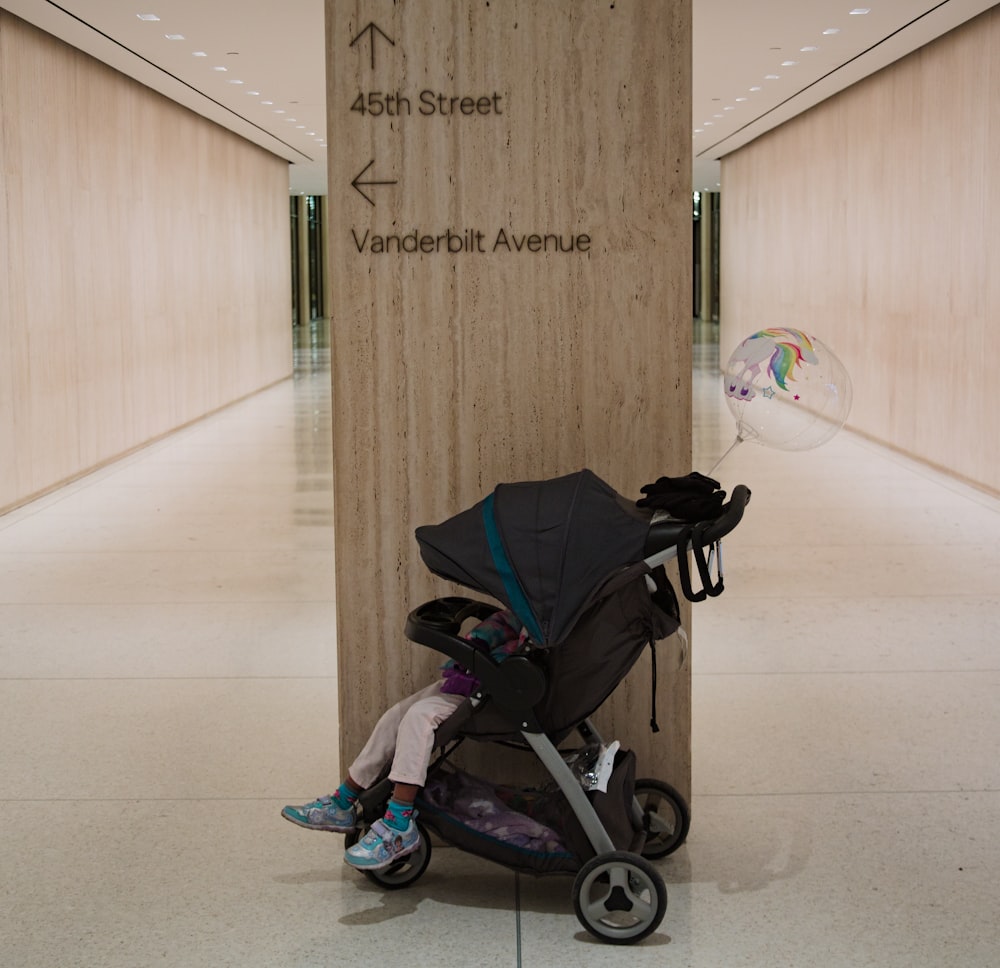 a baby in a stroller sitting in front of a sign