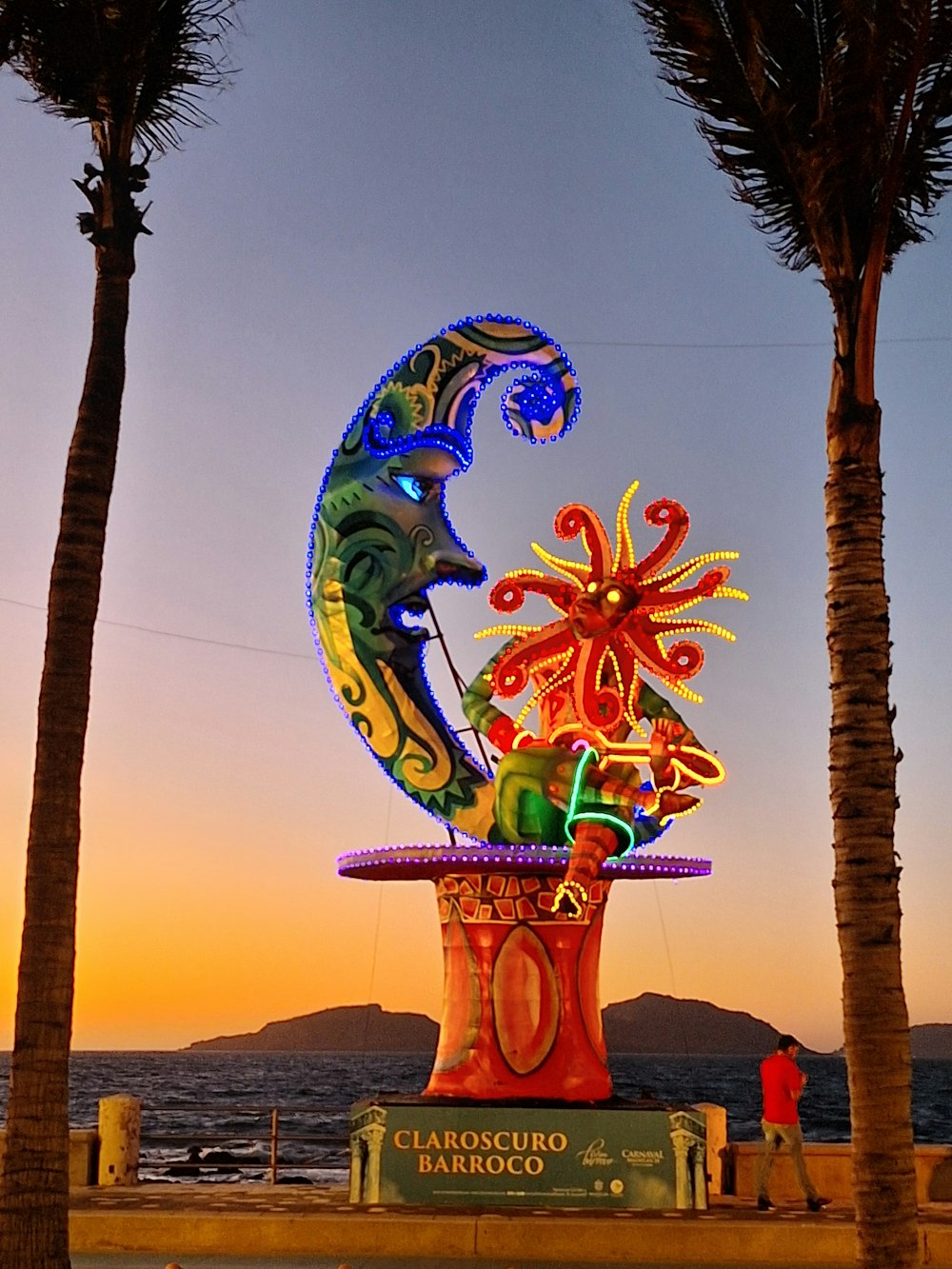 a colorful sculpture on the beach with palm trees