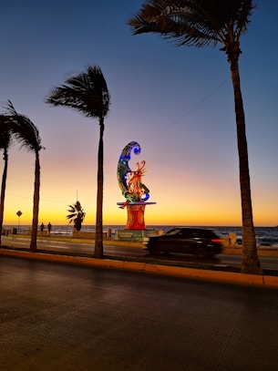 a car driving down a street next to palm trees