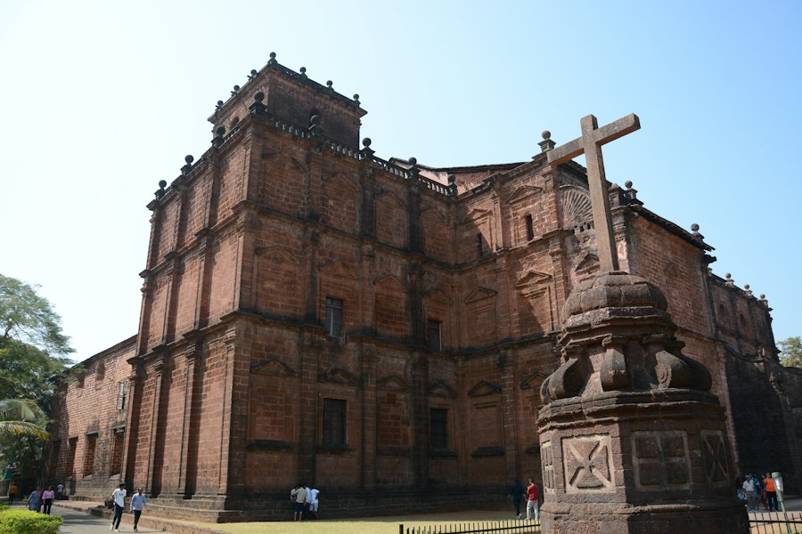 Basilica of Bom Jesus in Old Goa with its laterite facade and a stone cross in the foreground