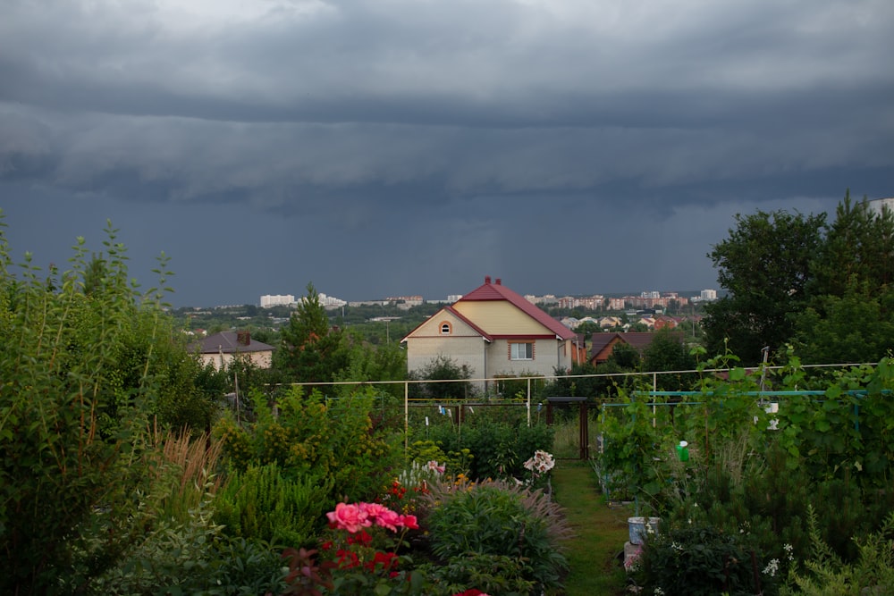 a house in the middle of a garden under a cloudy sky