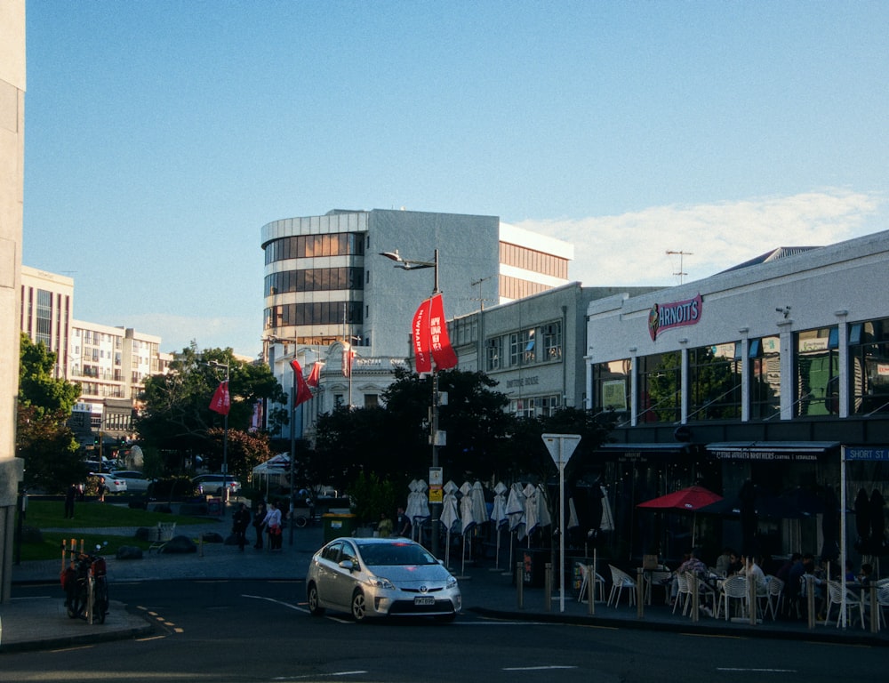 a white car driving down a street next to tall buildings