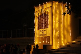 a group of people standing in front of a building with lights on it