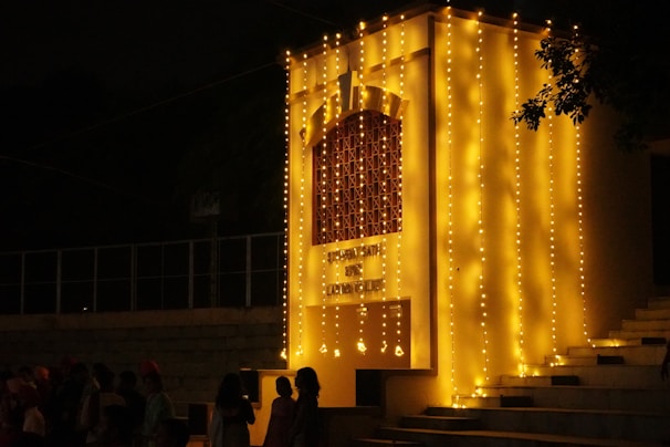 a group of people standing in front of a building with lights on it