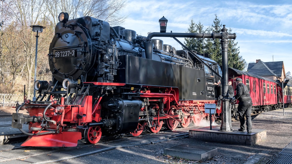 a man standing next to a black and red train