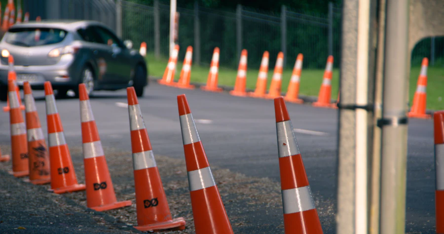 A car driving past a line of orange traffic cones