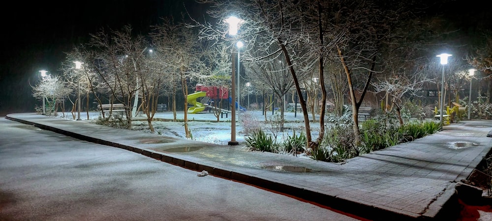 a snowy park at night with a playground in the background