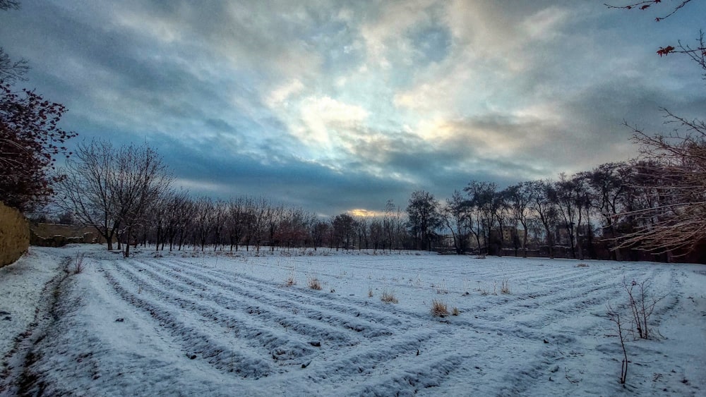 a field covered in snow under a cloudy sky