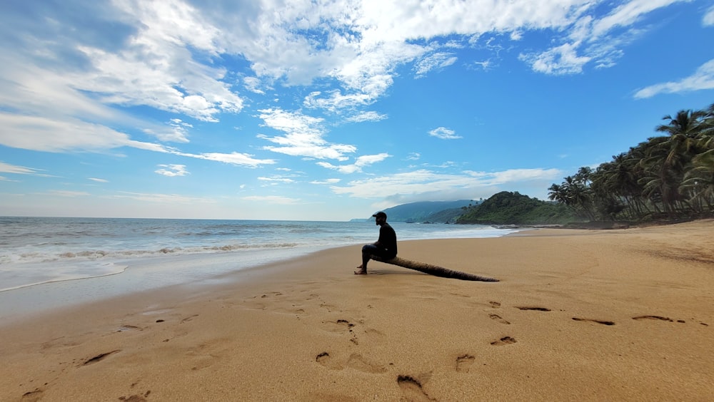 a person sitting on a log on a beach