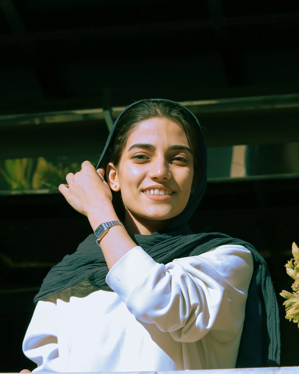 a woman in a hijab is smiling and holding a flower