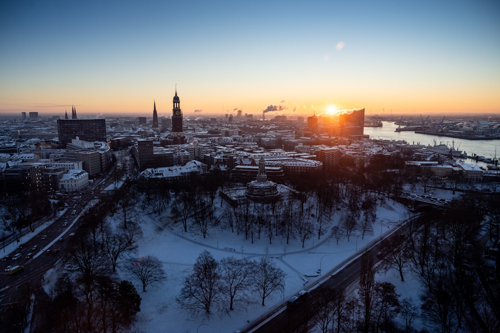 the sun is setting over a snowy city