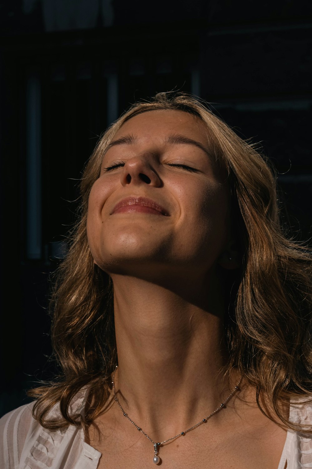 a woman with her eyes closed wearing a necklace