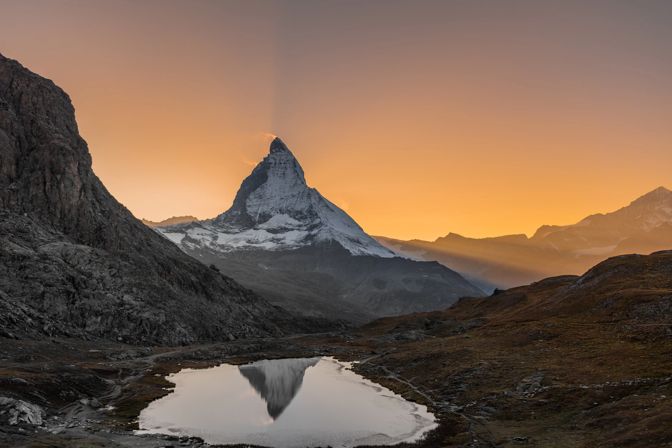 The Matterhorn reflected in a small tarn under an orange sunset