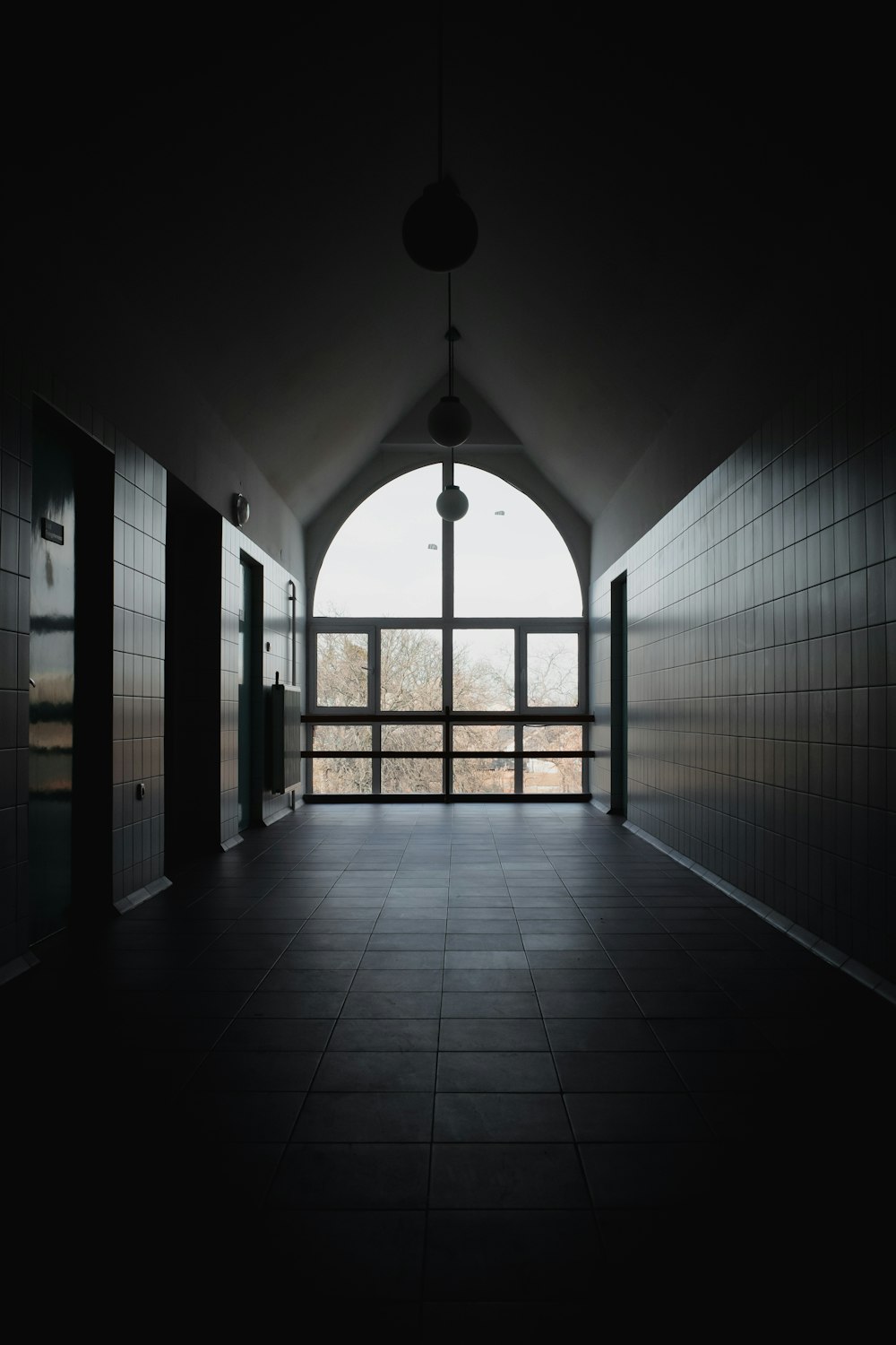 a dark hallway with a large arched window