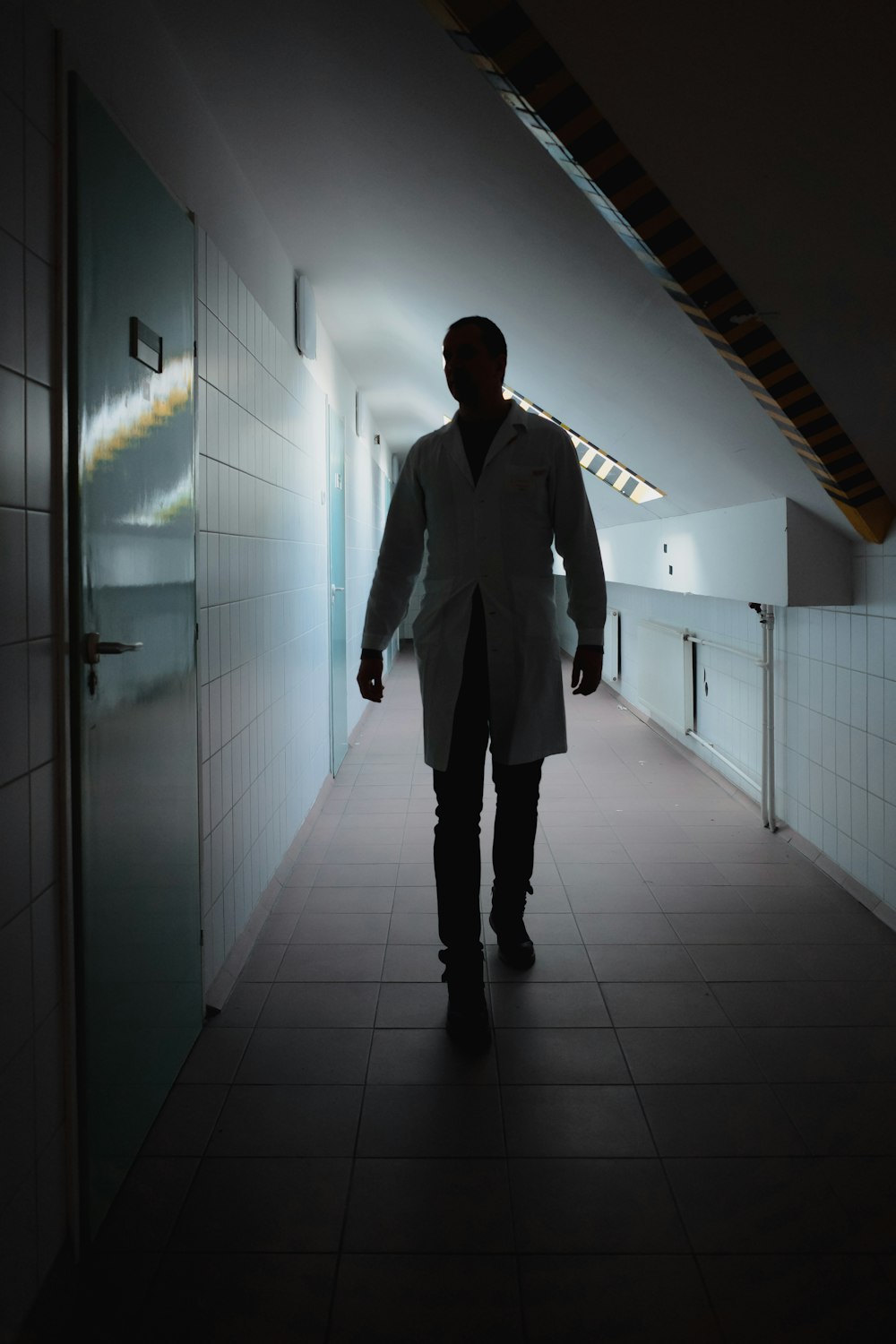 a man in a white coat walking down a hallway