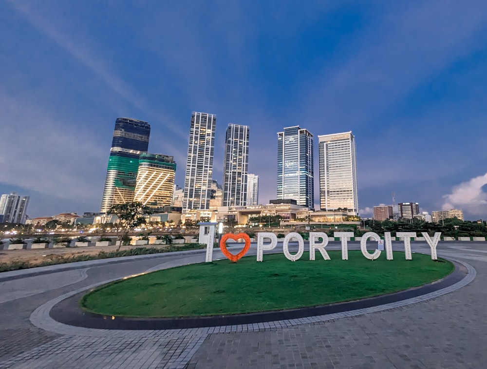 a sign that says i love port city in front of a cityscape