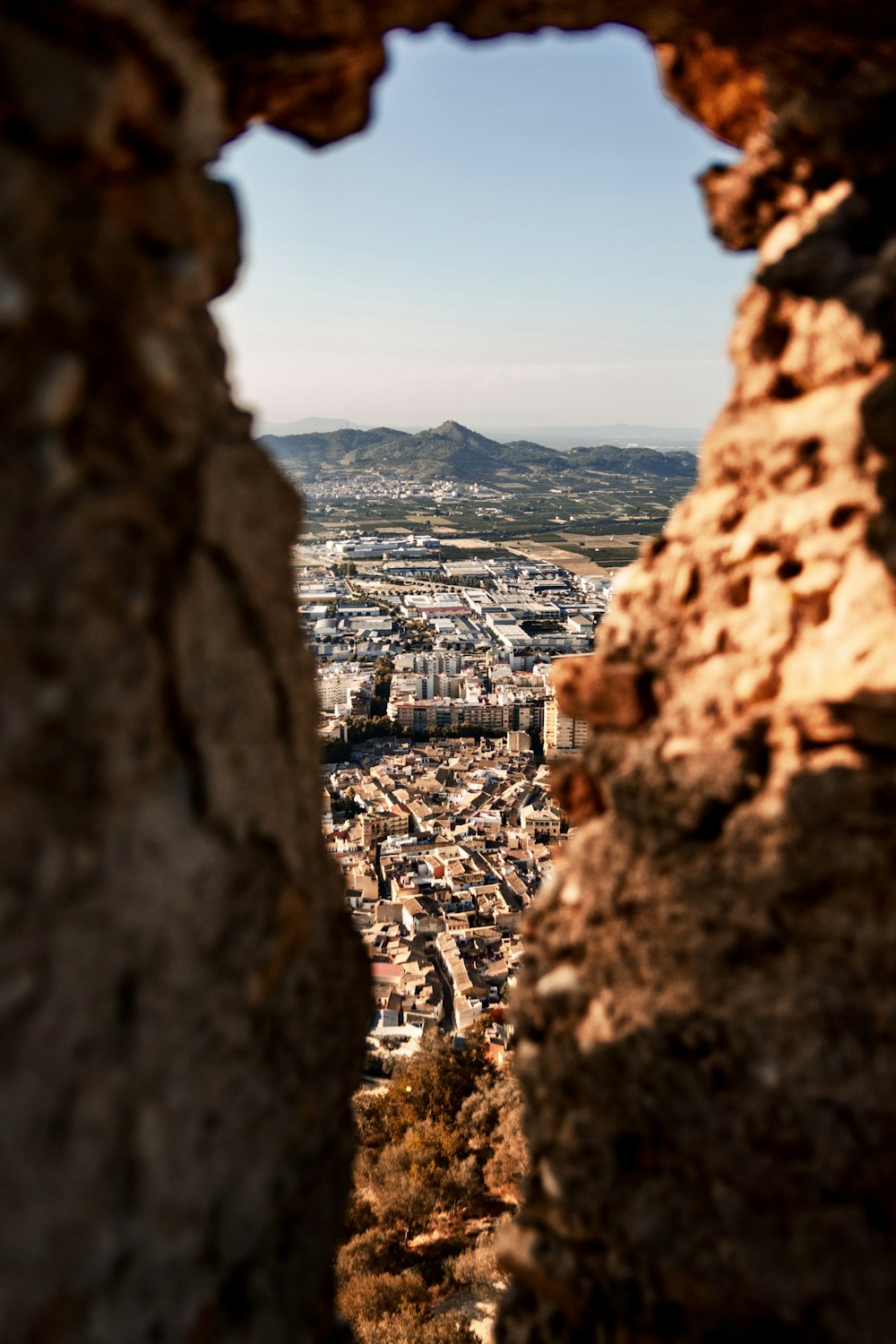 a view of a city through a hole in a stone wall