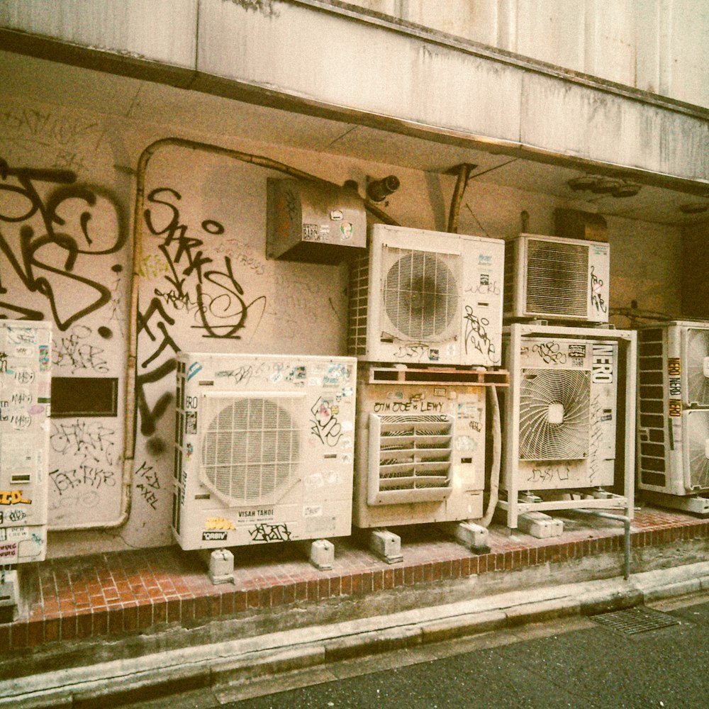 a bunch of old microwaves are lined up on the side of a building
