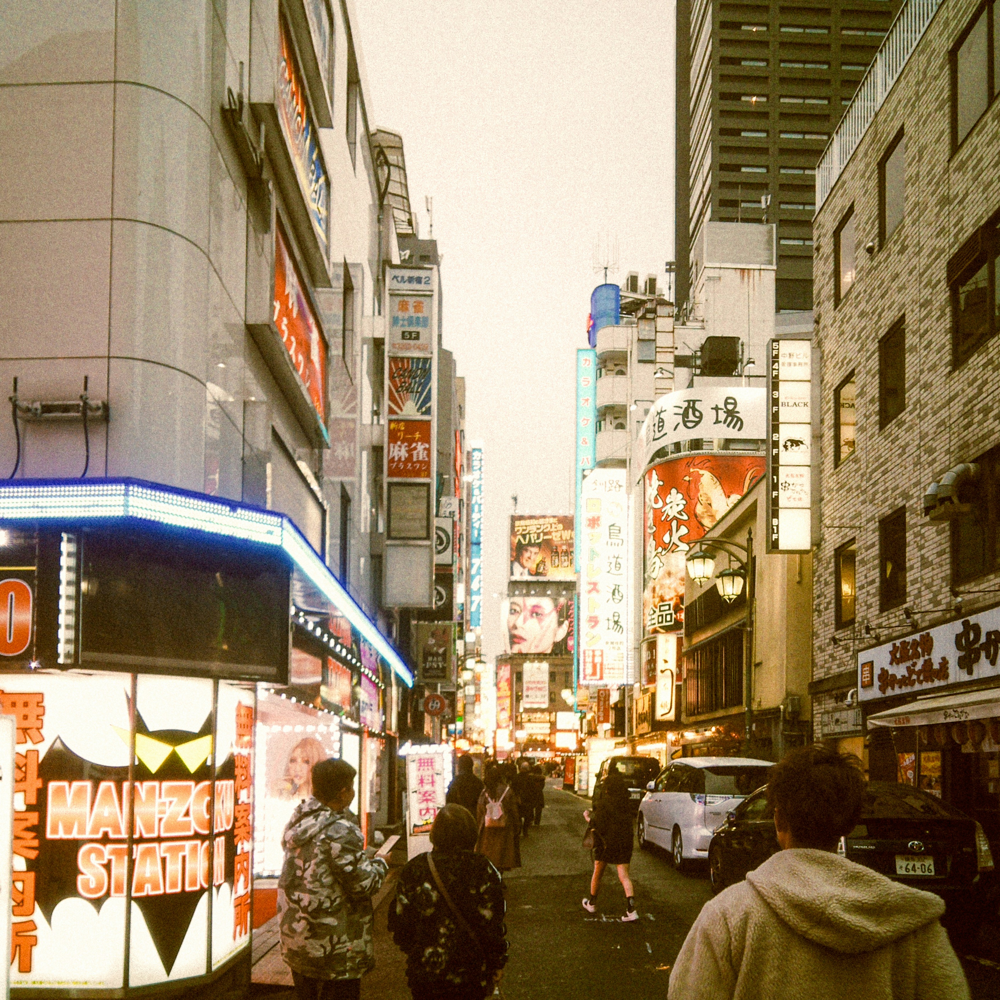 a group of people walking down a street next to tall buildings