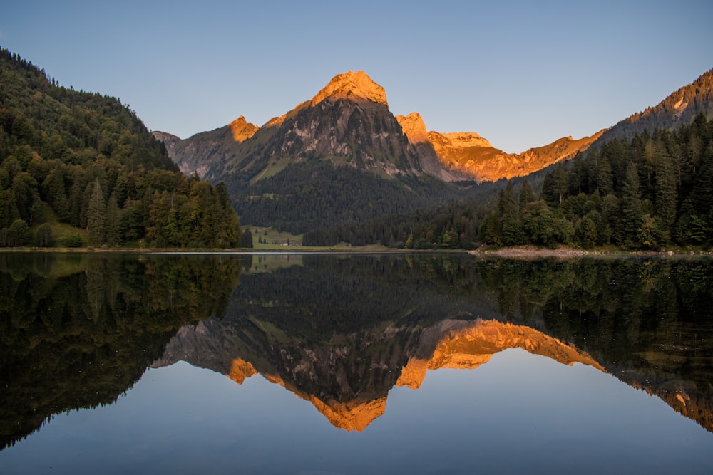 a mountain range is reflected in the still water of a lake