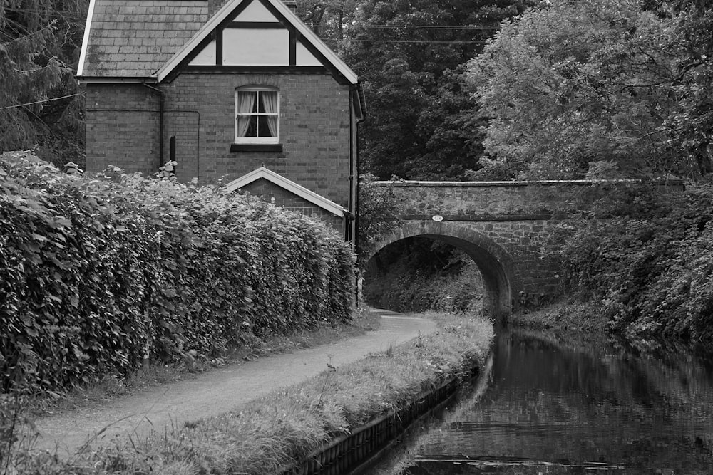 a black and white photo of a house next to a river