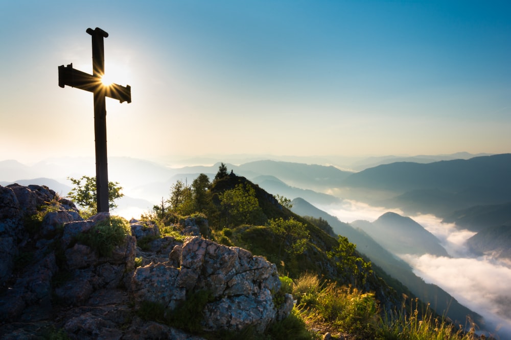 a cross on top of a mountain with a sky background