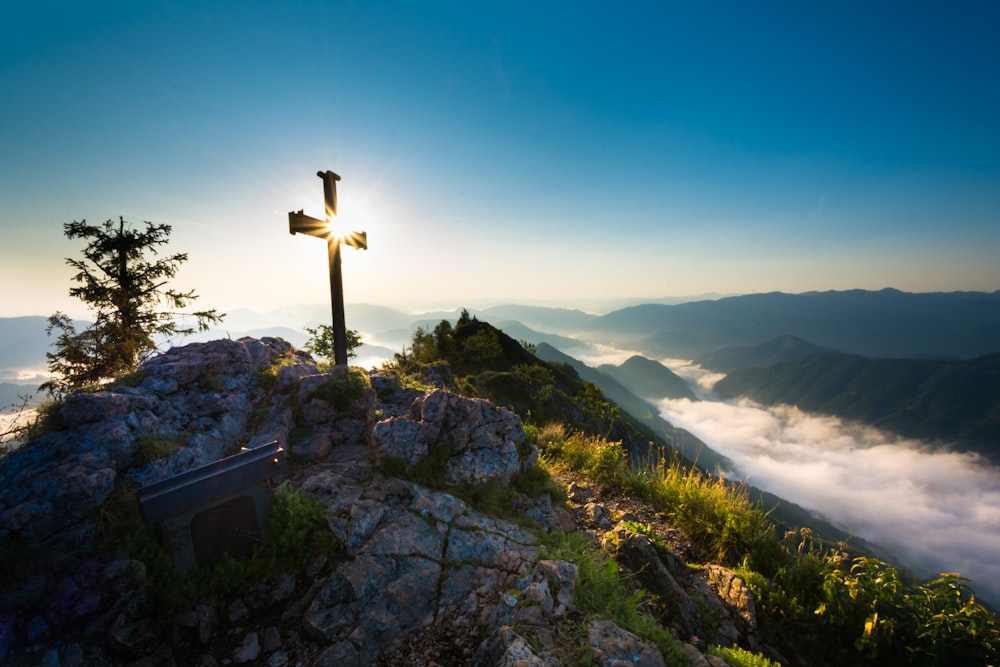 a cross on top of a mountain with a sky background