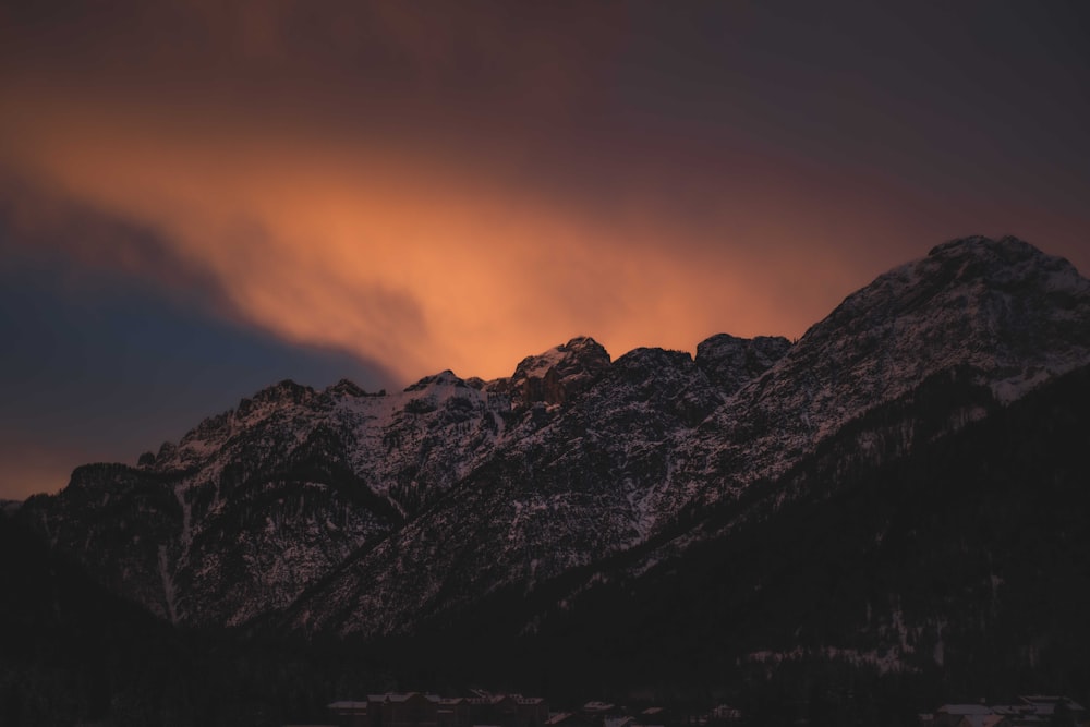 a mountain covered in snow under a cloudy sky