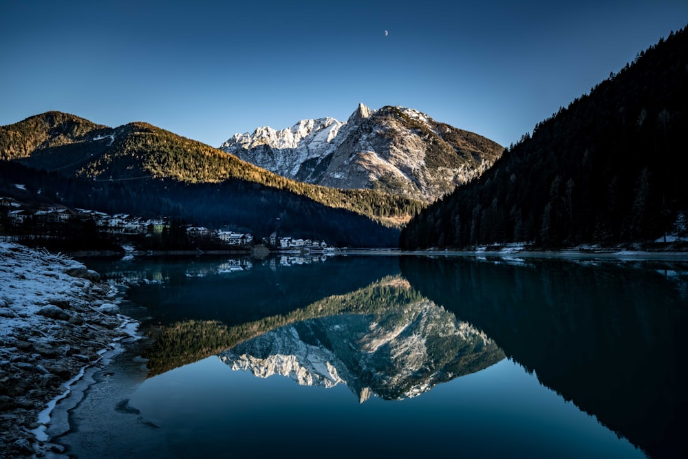 a mountain range is reflected in the still water of a lake