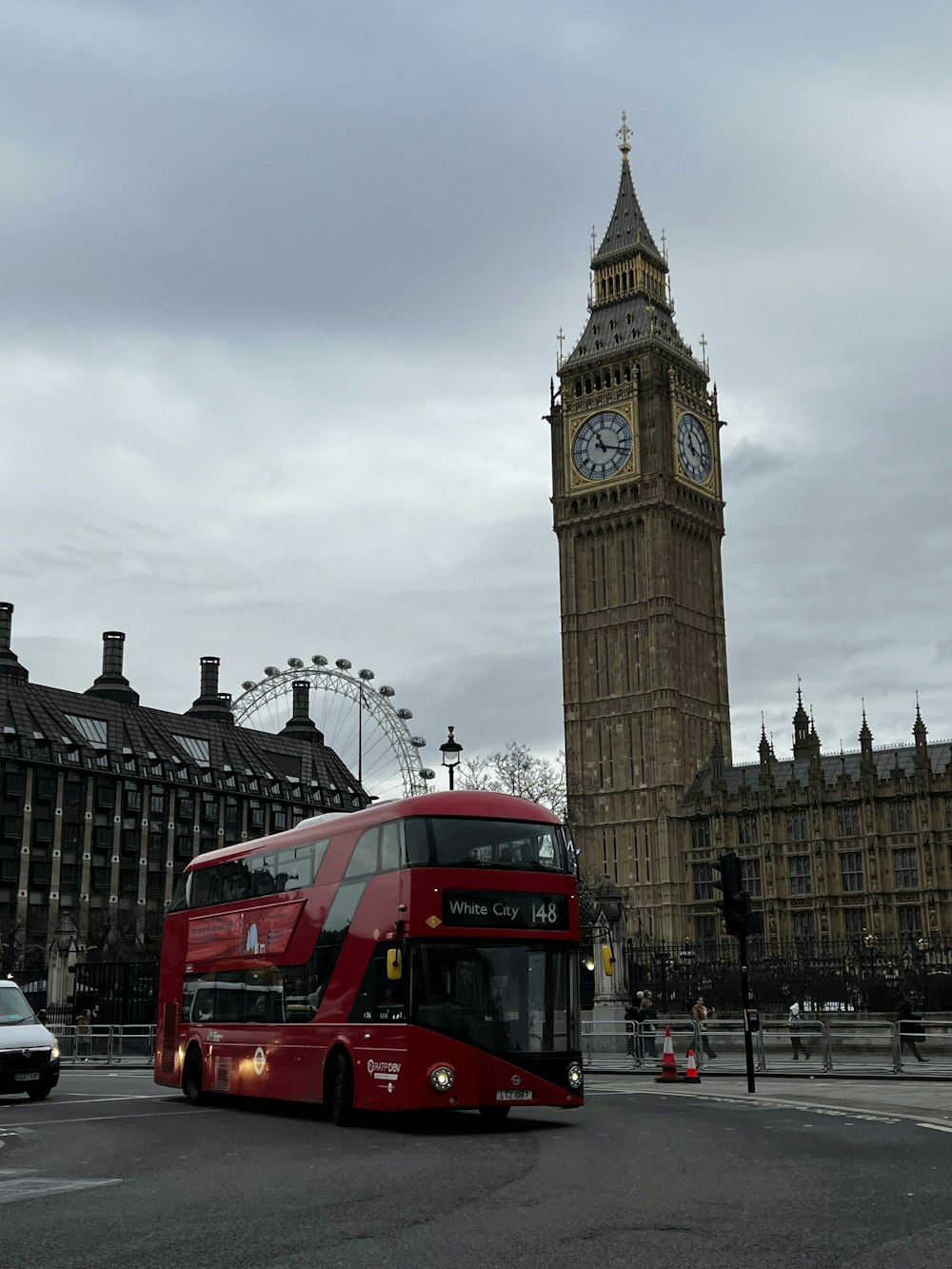 a red double decker bus driving past big ben