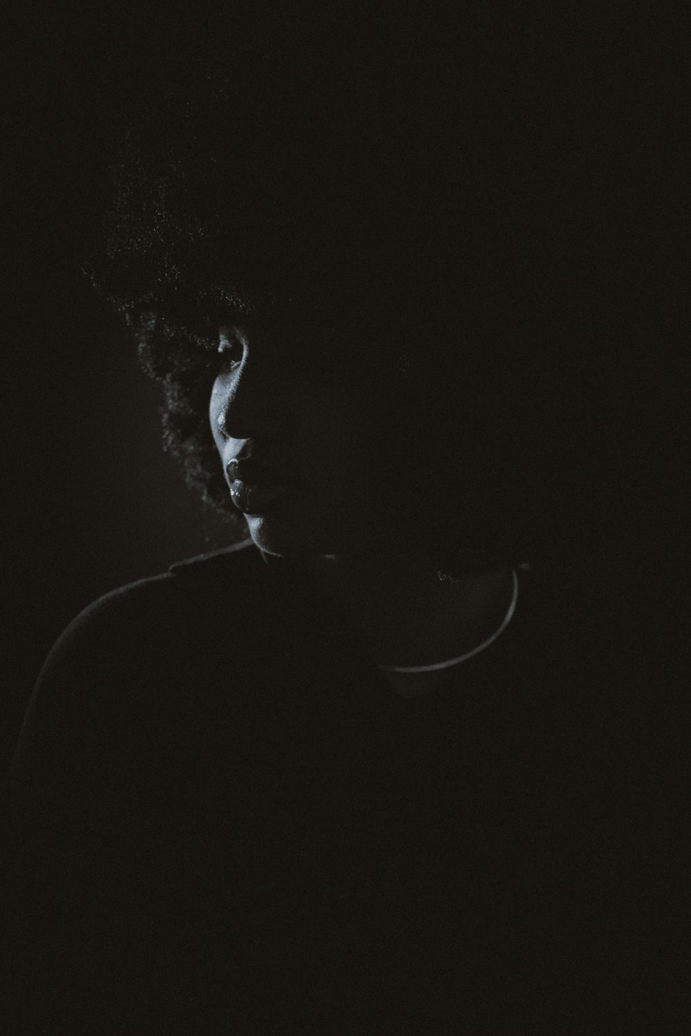 a man with curly hair standing in the dark