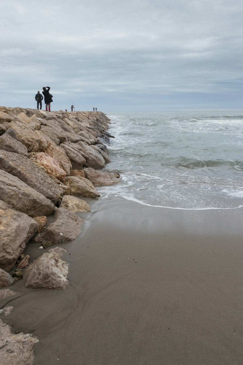 a group of people standing on top of a beach next to the ocean