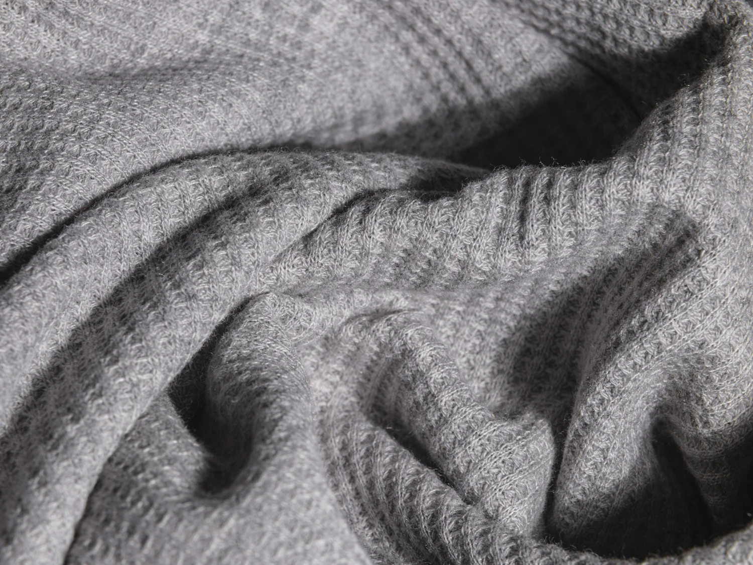 A grey knitted cloth falling in deep ridges