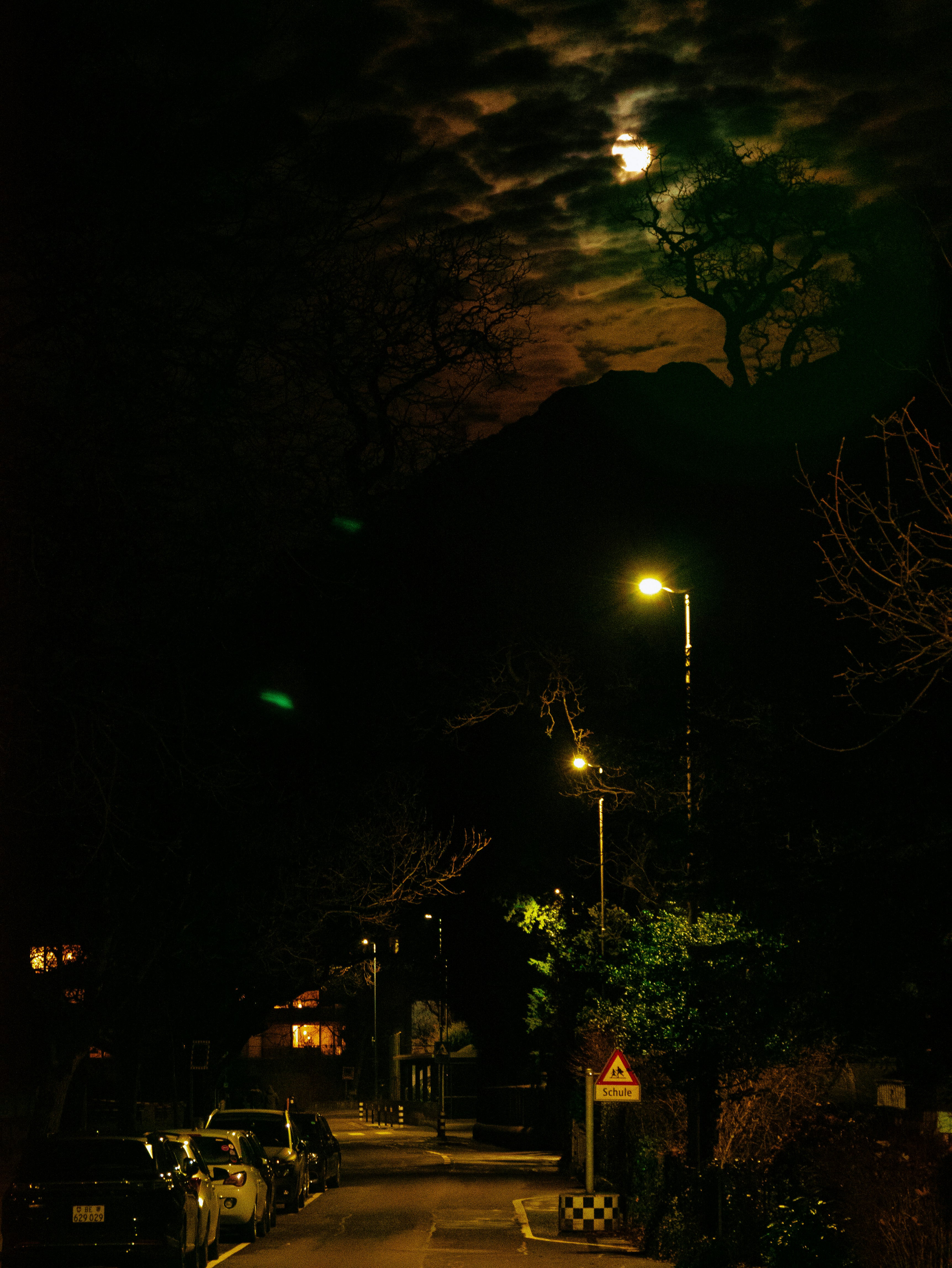a street at night with a full moon in the sky