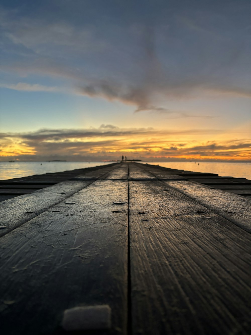 the sun is setting over the water on a pier