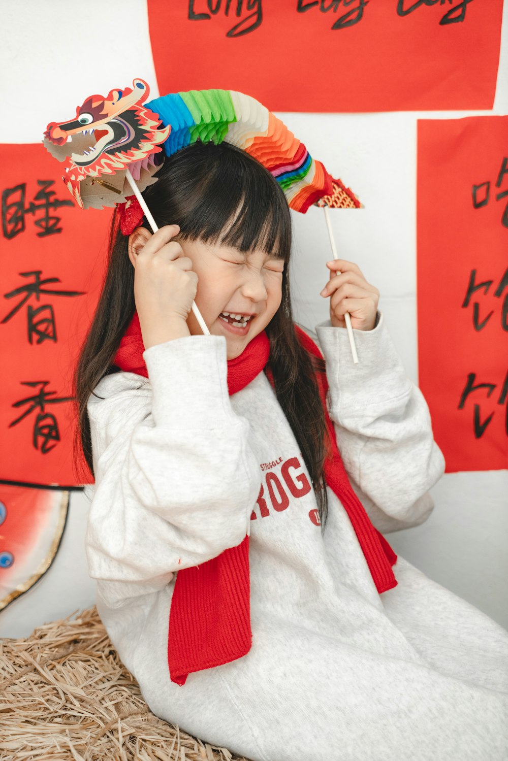 a young girl is holding a toothbrush and wearing a dragon headdress