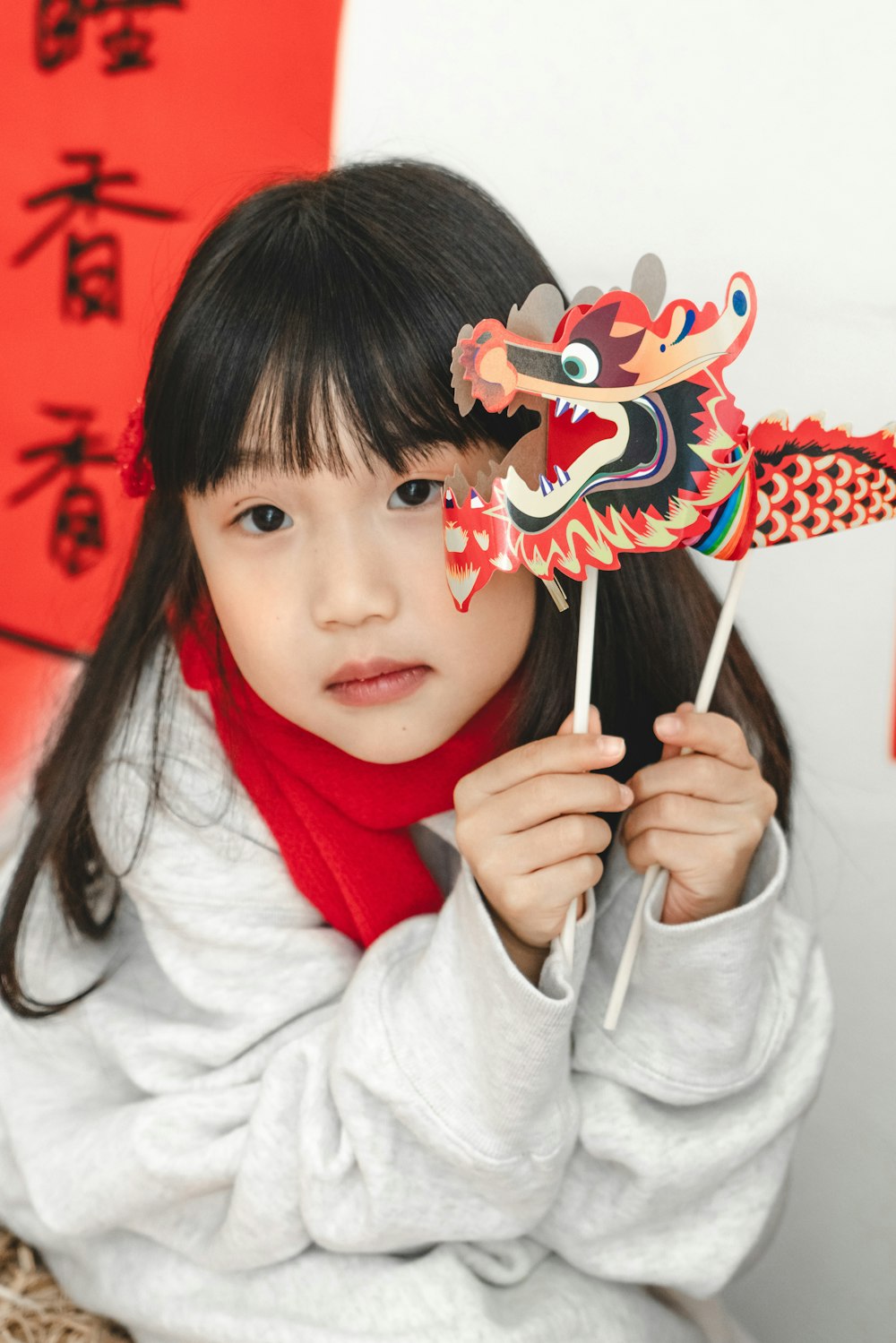 a young girl holding a dragon shaped pinwheel