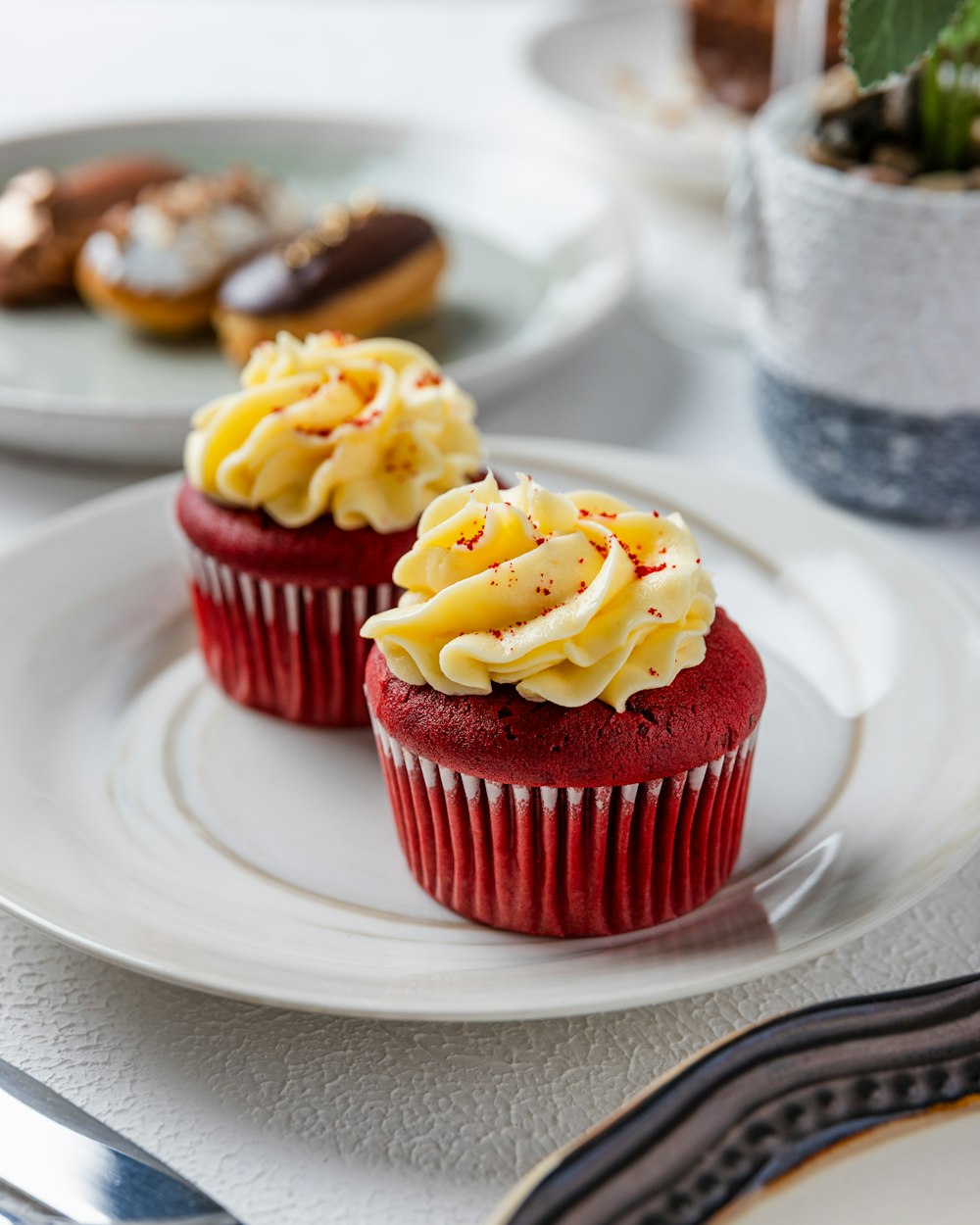 two red velvet cupcakes with white frosting and sprinkles