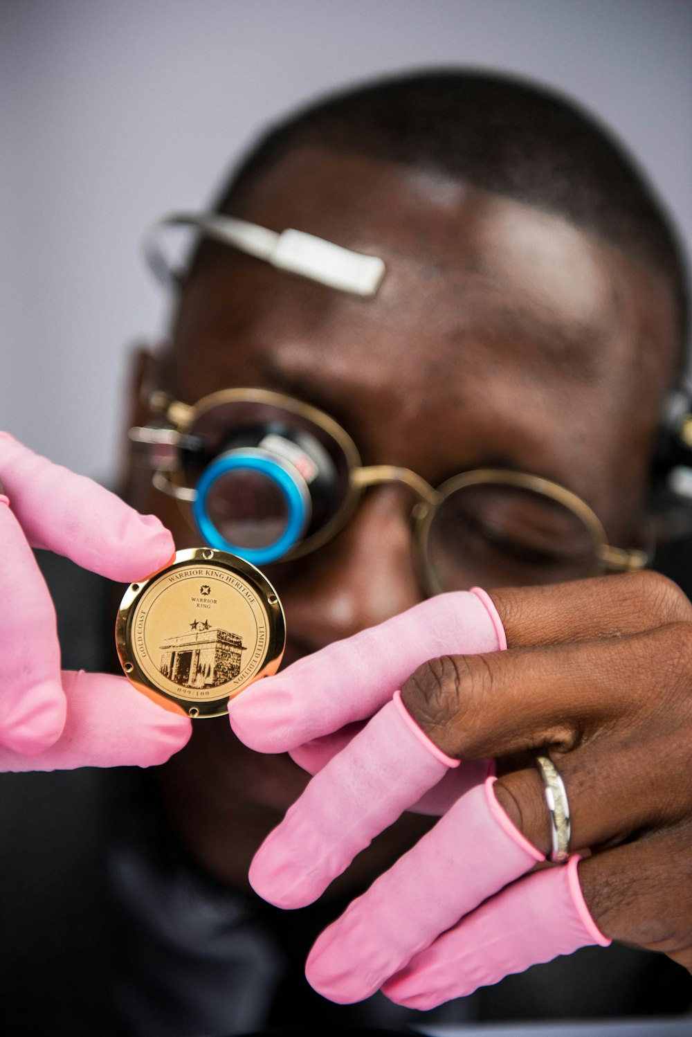 a man in pink gloves holding a gold medal