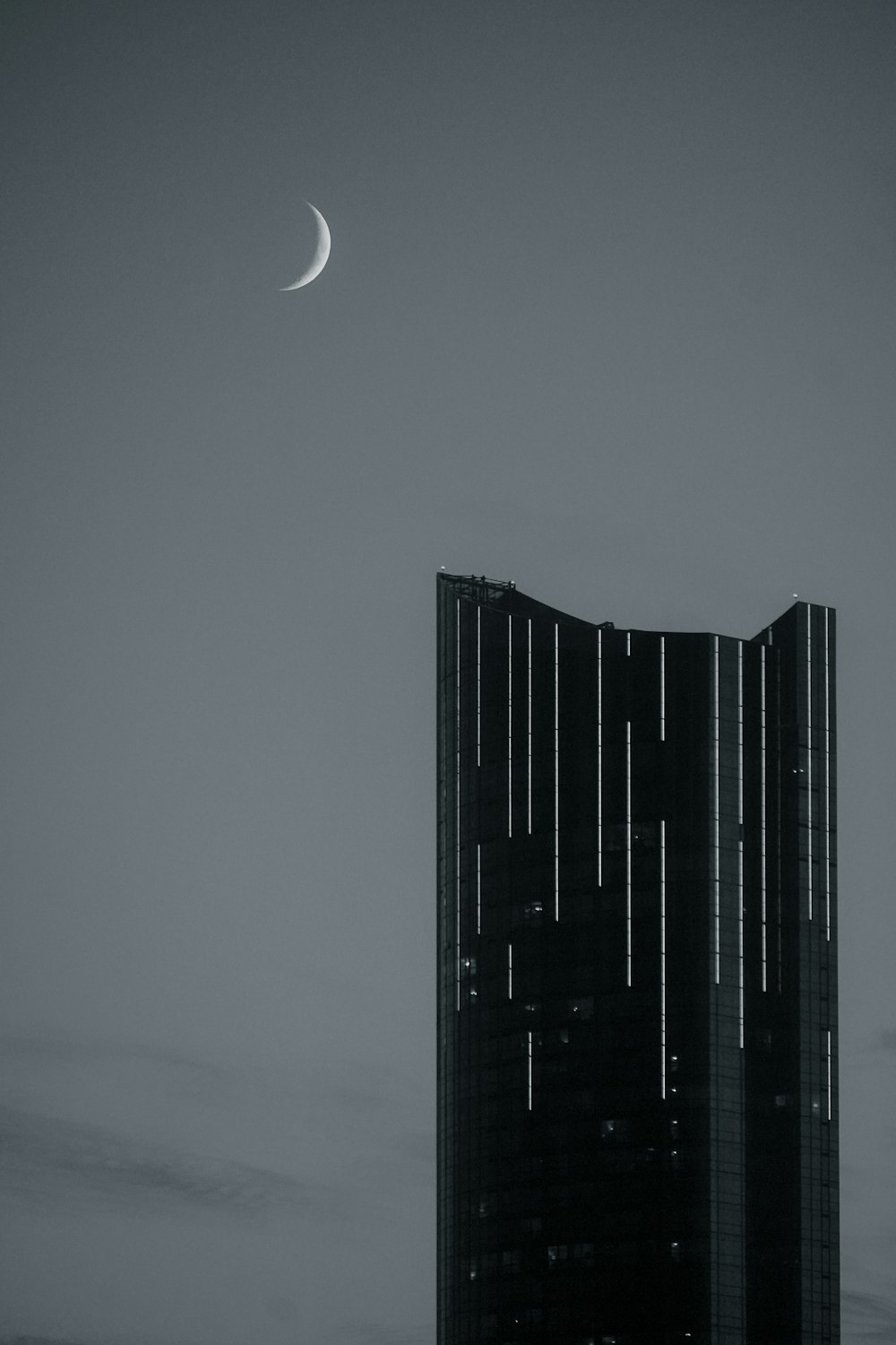 a very tall building with a half moon in the sky