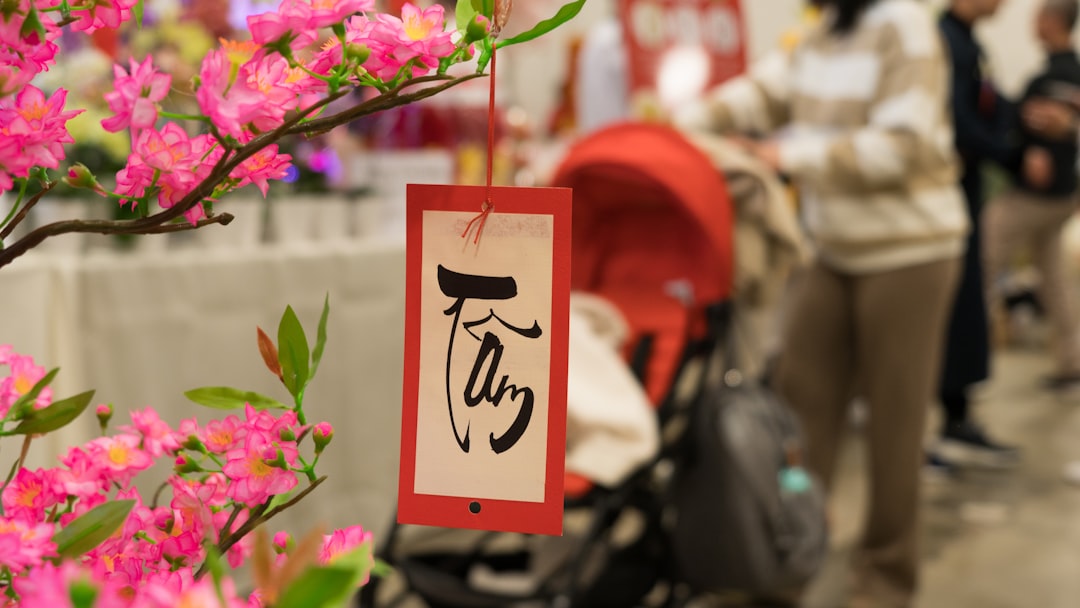 a sign hanging from a tree with pink flowers,